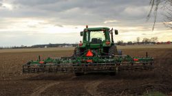 Green tractor with cultivator attached